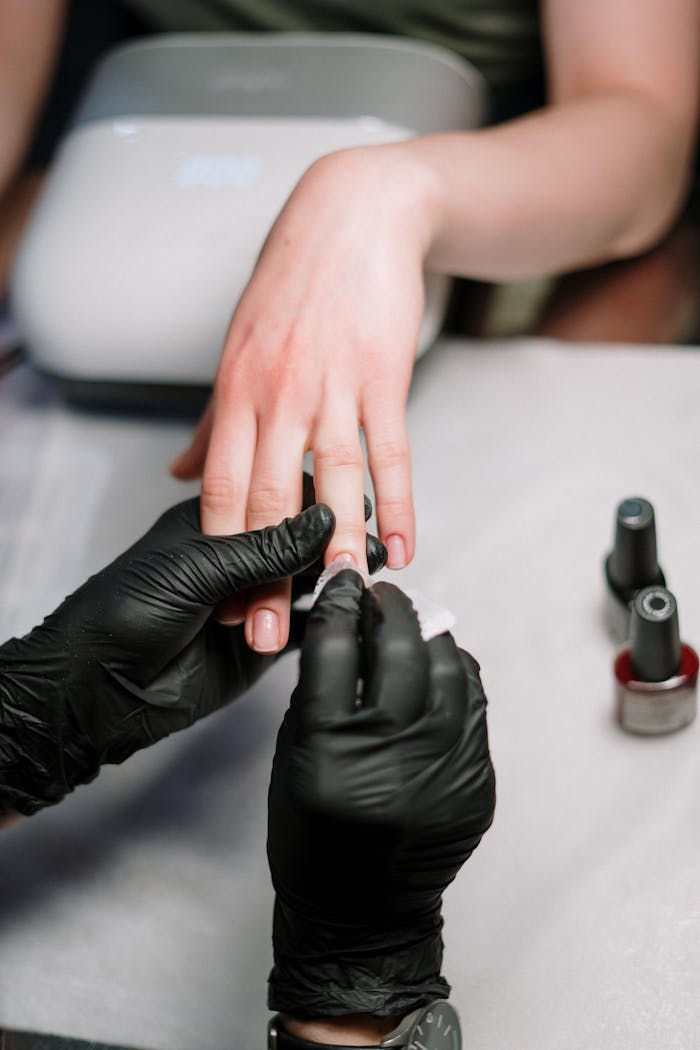 services-01 Close-up of a professional manicure with gel polish and black gloves in a salon.