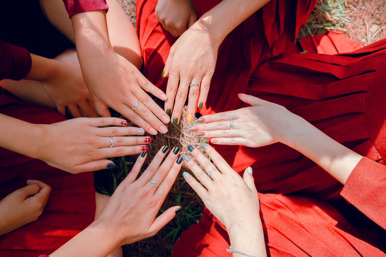 Home A vibrant top view of women showcasing painted nails and rings, emphasizing friendship and togetherness.
