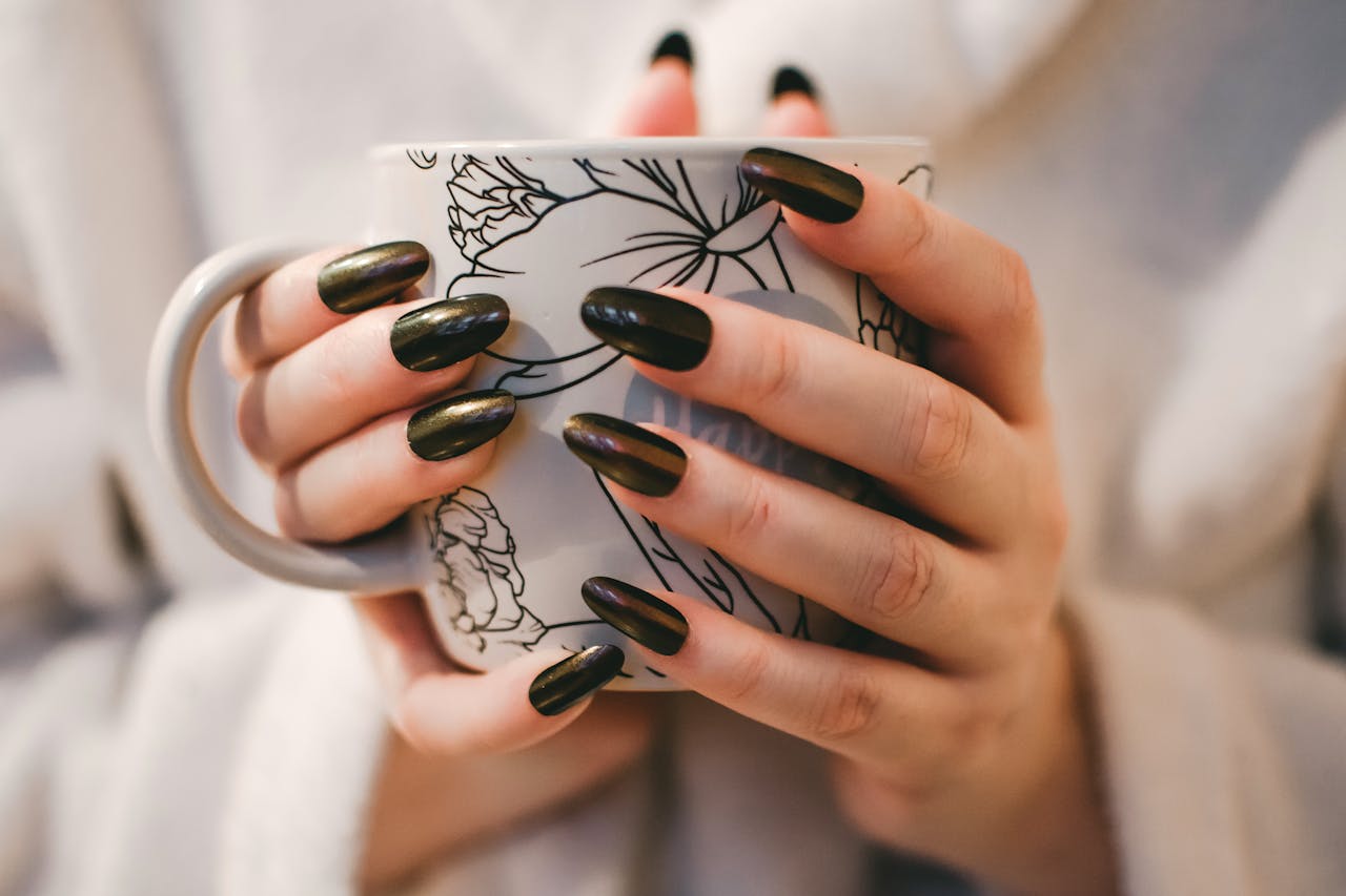 Home A close-up of manicured hands holding a decorative mug, perfect for lifestyle and coffee themes.